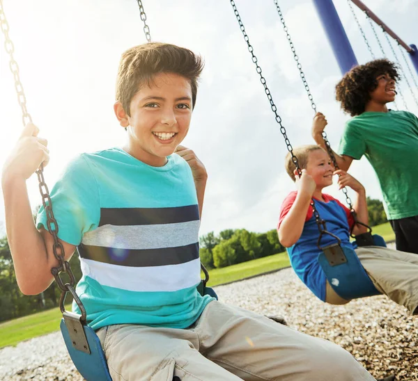 無料で 構造化されていない遊びは子供に不可欠です 友達と公園でスイングで遊んでいる若い男の子の肖像画 — ストック写真