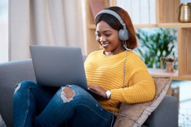 Dizüstü bilgisayarı, kulaklığı olan ve koltukta dinlenen siyahi bir kadın. İnternette film ve abonelik için arama yapıyor. Dairede mutlu bir Afrikalı kadın var, bağlantı kuruyor ve web üzerinden bilgisayar izliyor..