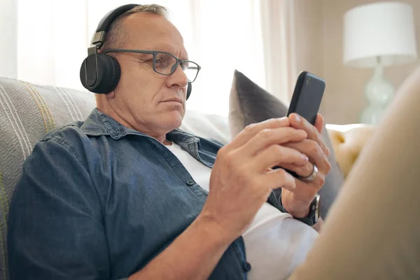 开始我的一天与一些曲调 一个老年人用智能手机听音乐 — 图库照片
