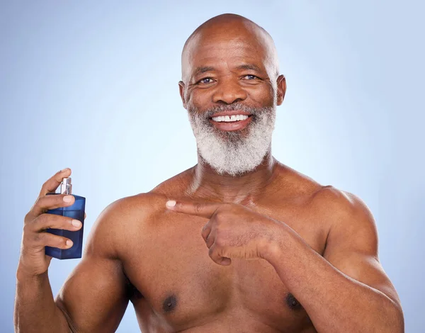 stock image A God-like scent. Studio portrait of a mature man spraying himself with aftershave against a blue background