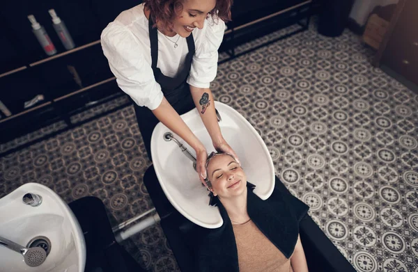 A trip to the salon will fix almost all your problems. a beautiful young woman getting her hair washed at the salon