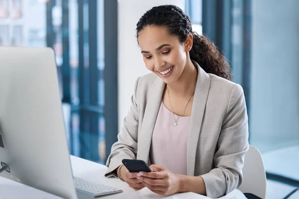 Young business woman, texting and phone in office with smile, email communication and chat with online date. Businesswoman, smartphone and typing for contact, networking and social media app at desk.