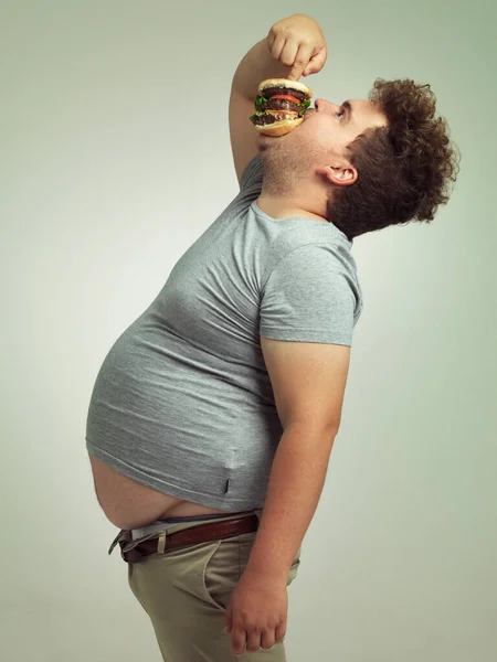 腹の中に入って スタジオショットの太りすぎの男ショットの彼の喉の下にハンバーガー — ストック写真