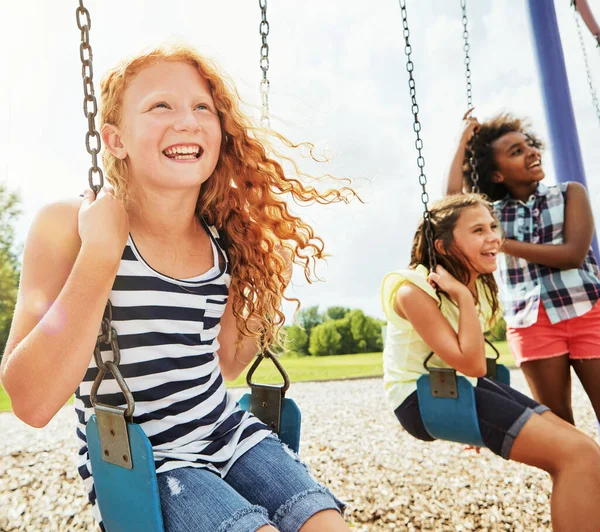 友達と楽しい時間しかない 公園でブランコに乗って遊んでいる若い女の子は — ストック写真