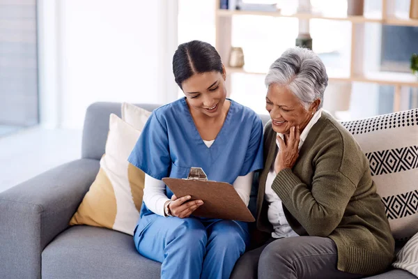Nurse, clipboard and senior woman with insurance for home and support with a smile on a couch. Nursing professional, documents and elderly person with caregiver for medical help for retirement