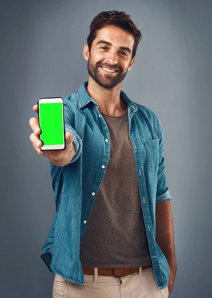 灰色のスタジオの背景に対する広告やマーケティングのための幸せな男 電話やモックアップ緑の画面 男性の笑顔の肖像画や広告のためのスマートフォンのディスプレイやクロマキーを表示します — ストック写真