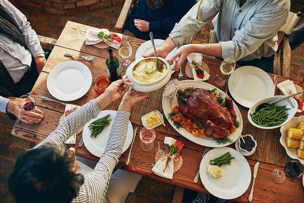 Food, table and family eating together for holiday celebration or dinner party with health vegetables. Above group of people or friends hands sharing lunch meal, chicken or turkey with wine drinks.