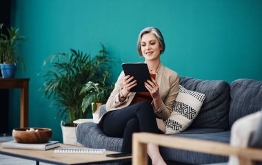 Şirket değişikliklerine ayak uydurmak. Çekici, olgun bir iş kadını yalnız başına oturuyor ve evinde tablet kullanıyor.