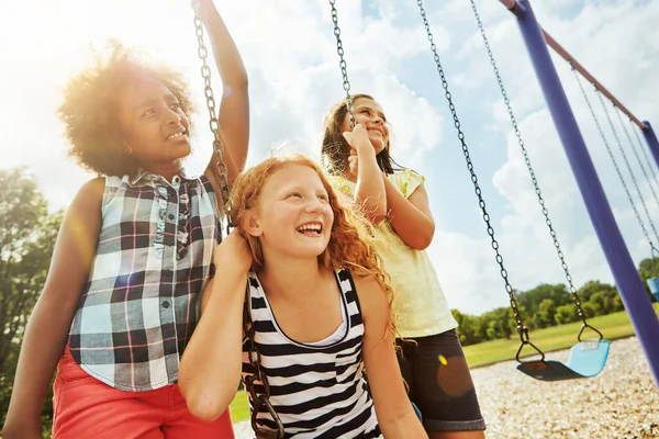 フルスイングで楽しい 公園でブランコに乗って遊んでいる若い女の子は — ストック写真