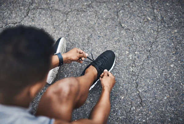 レースに出ましょう 屋外で運動しながら彼の靴ひもを結ぶスポーティ男の高角度ショット — ストック写真