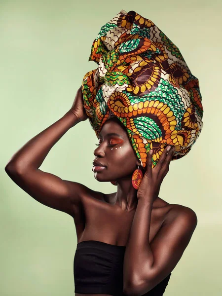 Culture, fashion and black woman in head wrap in studio for makeup, glow and cosmetics on green background. Face, beauty and african female model with pride, tradition and confidence isolated.