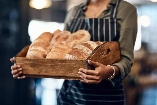 The crispiest buns around town. a woman holding a selection of freshly baked breads in her bakery