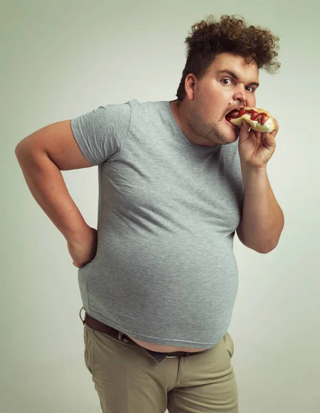 ホットドッグさんは私の胃に会います スタジオショットのA太りすぎ男食べるAホットドッグ — ストック写真