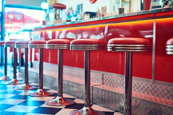 Trendy, vintage and retro interior in a diner, restaurant or cafeteria with funky decor. Booth, old school and chairs by a counter or bar in a groovy, vibrant and stylish old fashioned empty cafe