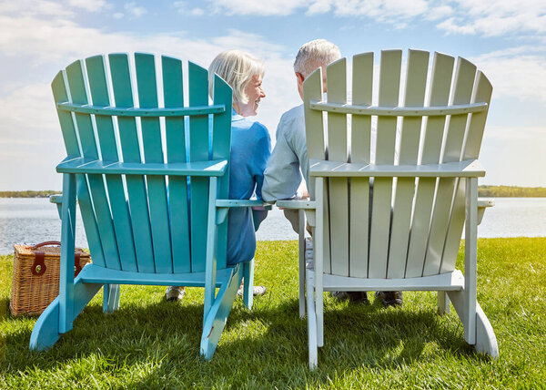 Nothing says retirement like a vacation at the lake. an affectionate senior couple relaxing on chairs together outside