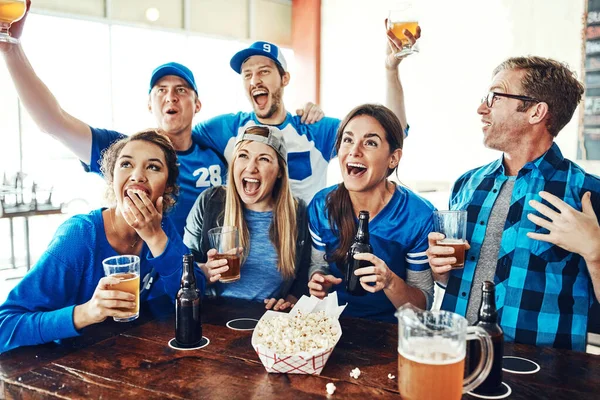 It wouldnt be sport without the fans. a group of friends cheering while watching a sports game at a bar