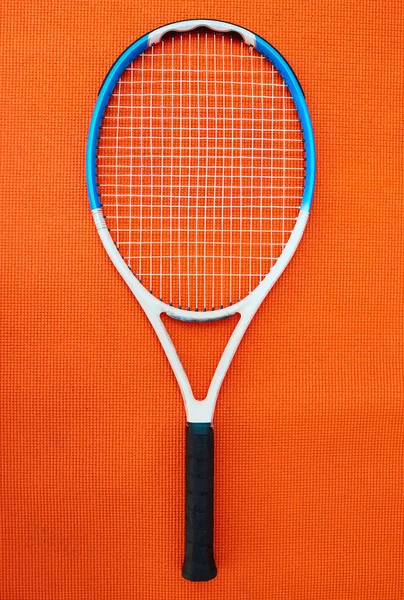 その種の最高のもの スタジオ内のオレンジの背景に置かれたテニスラケットの高い角度のショット — ストック写真