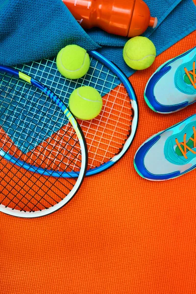 その日の訓練を終えた スタジオ内のオレンジの背景の上に配置されたテニス必需品の高角度ショット — ストック写真