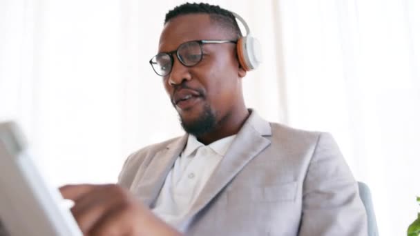 プレイリストやアルバムを聞いてオフィスでタブレット ヘッドフォンや黒人男性 ダンス テクノロジー プロフェッショナルアフリカのビジネス男性従業員が職場でオンラインで歌やビデオをストリーミング — ストック動画