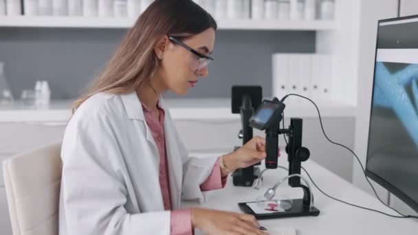 Forschung Mikroskop Und Computer Mit Einer Frau Die Notizen Schreibt — Stockvideo