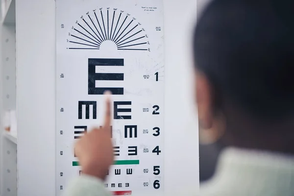Eye care, medical and chart for a vision test for prescription lens glasses in an optometry clinic. Ophthalmology, healthcare and back of optometrist doing an optical exam with letter board in store
