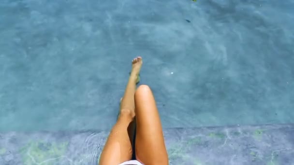 夏の色合いのスイミングプールでリラックスした女性 美しく 自信のあるビキニレディは 髪の毛のない足と日焼けした肌で水を楽しんでいます 休日のための滑らかで放射状の皮膚 — ストック動画