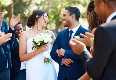 Evlilik töreni, çiftler ve insanlar aşk, romantizm ve birlikteliği kutlamak için el çırpıyorlar. Mutlu, gülümseyen ve damat buketi olan bir gelin açık havada evlilik için tezahürat yapan misafirlerin yanından geçiyor..