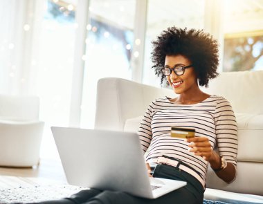 Genç bir kadın, dizüstü bilgisayar ve kredi kartı oturma odasında online alışveriş yapıyor. İnternet ekommerce uygulaması üzerinden internet üzerinden çalışan Afrikalı bir kadının ev, mutluluk ve bilgisayarı..