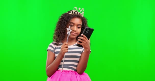 背景のモックアップに隔離されたスタジオで緑の画面と魔法の杖を持つ電話 女の子と王女 王冠とティアラと子供と携帯電話のためのソーシャルメディアやクロマキー上のオンラインブラウジング — ストック動画