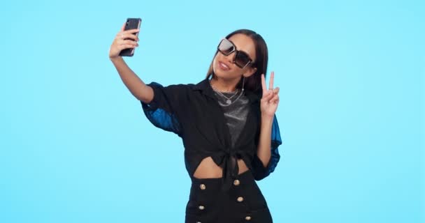 Selfie Solbriller Kvinne Med Fredskilt Isolert Blå Bakgrunn Selvfotografering Håndbevegelse – stockvideo