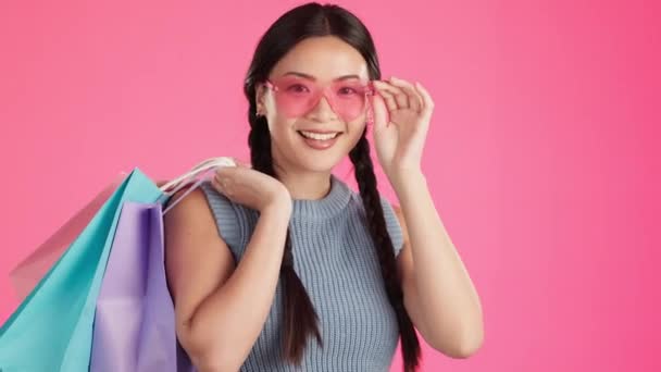 工作室和亚洲女性肖像画对服装销售和购物袋感到满意 与一个年轻的 女性和基因Z模型 与交易和销售袋隔离 粉红背景和时尚 — 图库视频影像