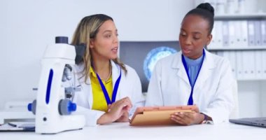 Bilim adamları ve kadınlar tıbbi araştırma işbirliği ile tablet ve bilim çalışmalarının sonuçlarını analiz ederler. Laboratuvarda tartışılan kadın, bilimsel yenilik ve deney ve analiz ile takım çalışması.