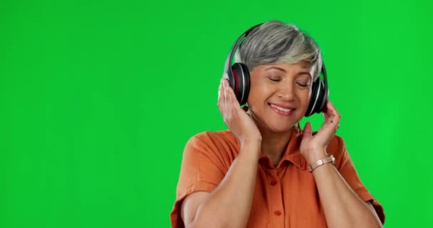 スタジオでヘッドフォンダンスを持つ音楽 緑の画面と高齢者の女性 幸せとモックアップの背景に無料 ラジオ ポッドキャスト シニア女性のダンス オンラインサブスクリプションでストリーミングと冷却 — ストック動画