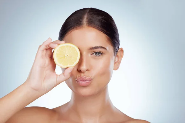 Face kiss, skincare and woman with lemon in studio isolated on a white background. Portrait, natural and female model with fruit for vitamin c, nutrition or healthy diet, wellness or cosmetics pout