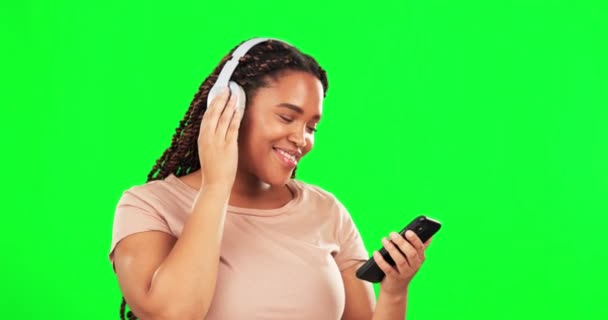 幸せな女性 緑の画面と電話 ヘッドフォンやラジオをオンラインで聞くとダンス ダンス 女性モデル 携帯電話で音楽を聴く オーディオサウンドとリラックスした気分のためのエネルギーをストリーミング — ストック動画