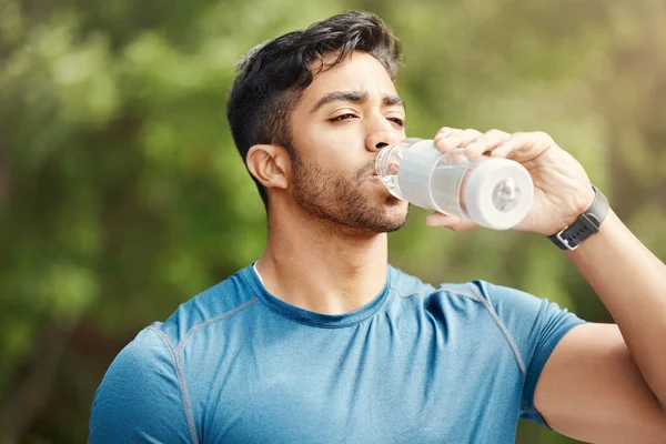 stock image Fitness, man with in park, drinking water and hiking in nature for health and wellness during exercise. Drink, bottle and fit male on hike with trees for body workout, energy and training mindset