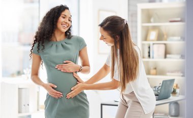 Happy, kadın hamile arkadaşını ve modern işyerindeki bir ofiste mercek ışığıyla ziyaret ediyor. Bebek bakımı ya da sağlık hizmetleri sağlık, mutluluk ve iş yerinde birlikte mide büyümesi olan arkadaşlar.