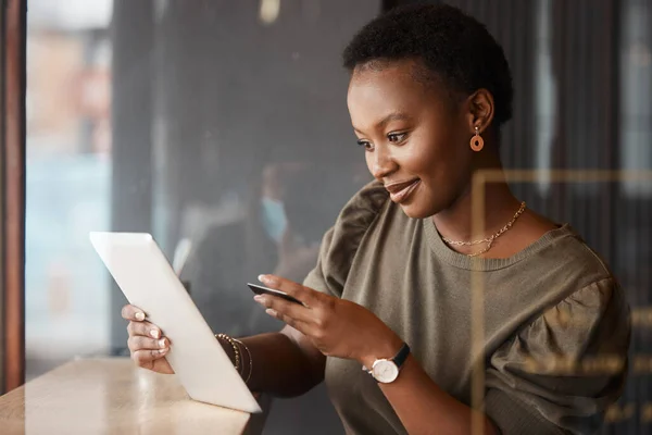 Tablet, credit card and black woman at a coffee shop with technology and ecommerce app. Online shopping, African female person and digital payment in a cafe and restaurant with tech and website deal.