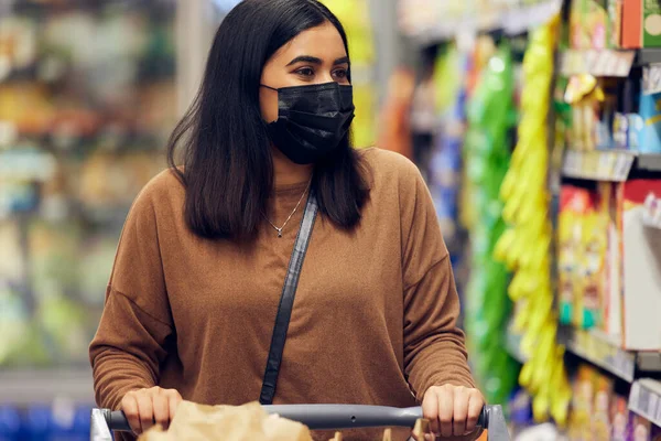 杂货采购 妇女和购物车在零售店 市场和商店的杂货带着面具 病毒安全及可在货架超级市场购买的可选择食物的女性人士 — 图库照片