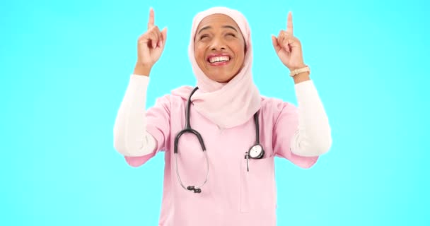 穆斯林护士 快乐的女人和手指肖像与医疗保健 宗教或幸福的空间 带着双手 微笑和头巾的伊斯兰女性医务工作者发布蓝色背景的通告 — 图库视频影像