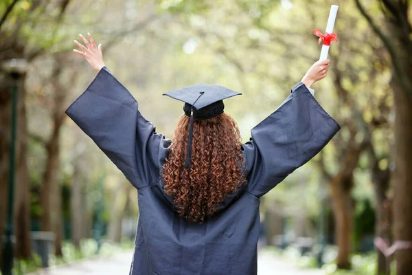 Celebration, back view of university student and with certificate outdoors. Success or achievement, graduate or happiness and winner woman at college campus outside on graduation day for diploma.