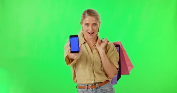 スタジオの背景にトラッキングマーカーと緑の画面上の女性 電話やショッピングバッグ モックアップ上のオンラインショッピングや電子商取引のためのスマートフォンのディスプレイやギフトバッグと幸せな女性の肖像画 — ストック動画