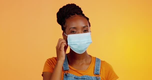 顔のマスクと幸せな黒人女性の予防接種 治癒し 健康的なポストパンデミックを削除します 肖像画 医学ワクチンの成功とオレンジの背景にウイルス安全ポリシーの終わりを持つスタジオの人 — ストック動画