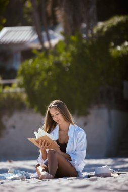 Kumsalda kitap okuyan ve seyahat eden bir kadın yaz tatilinde huzur ve sükunetle doğada dinlenir. Genç bayan dışarıda, okuyacak bir romanı, deniz kenarında bir tatili ve güneşte dinlenmesi var..