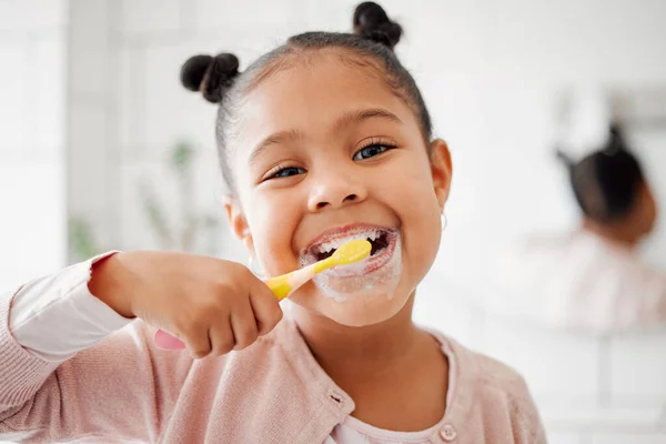Toothbrush, brushing teeth and face of a child in a home bathroom for dental health and wellness. Smile portrait of african girl kid cleaning mouth with a brush for morning routine and oral self care.