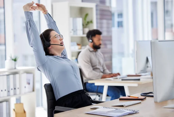 Customer service, woman with headset and stretching her arms at her desk with a computer of modern workplace. Online communication, telemarketing and female call center agent stretch for fatigue.