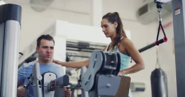 Spor salonu, erkek ve kişisel antrenör birlikte egzersiz yapar, spor yapar ve kilo vermek ve sağlıklı olmak için antrenman yaparlar. Koç kadın ve müşteri sağlık ve sağlık için kürek çekme makinesinde motivasyon, yardım veya destek.