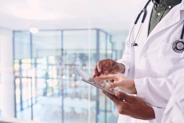 Tıbbı ilerletmek için teknolojiyi kullanmak. Hastanede dikilirken dijital tablet üzerinde çalışan tanınmayan iki doktor.
