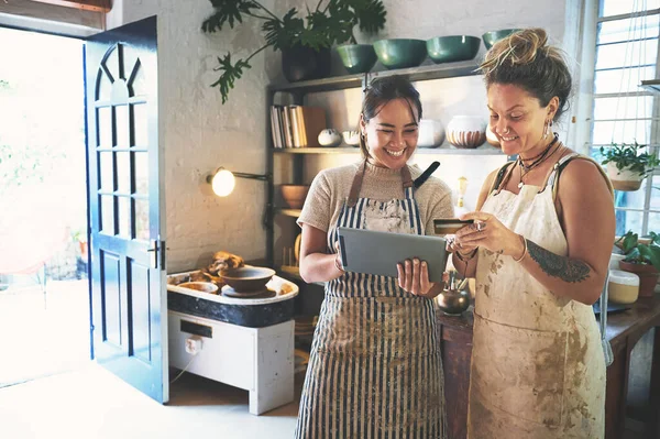 stock image As easy as paying for pottery supplies gets. two young women using a digital tablet and credit card while working together in a pottery studio