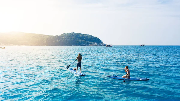 夏はスタンドアップパドルボードのためです 海を渡る男と女のパドルボード — ストック写真
